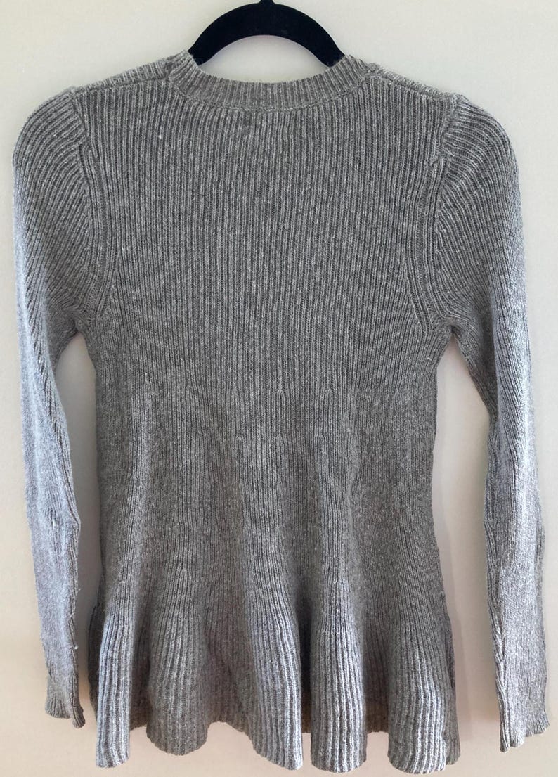 May include: A gray ribbed knit sweater with a ruffled hem.