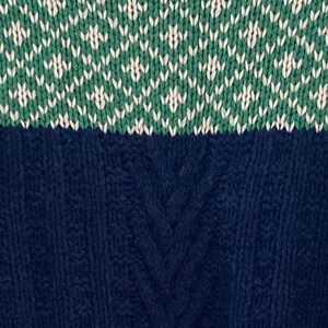 May include: A blue and green knitted sweater with a cable knit pattern on the bottom half and a diamond pattern on the top half.