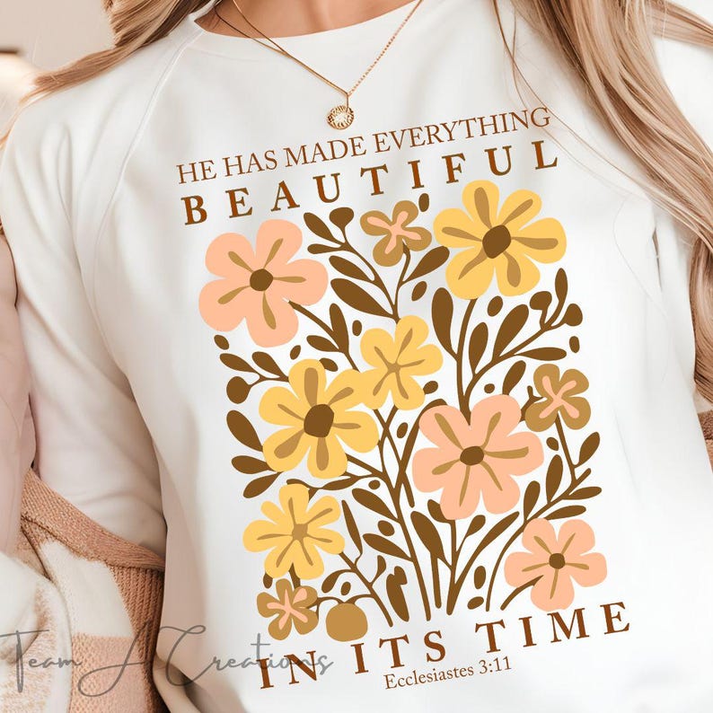 Puede incluir: Sudadera blanca con un dise&ntilde;o floral y el texto "&Eacute;l ha hecho todo hermoso en su tiempo, Eclesiast&eacute;s 3:11".