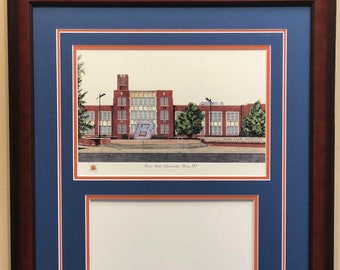 May include: A framed print of a building with a large blue "B" in front of it. The print is titled "Boise State University, Boise ID". The frame is dark brown with a blue mount and a white inner mount. The bottom of the frame has the words "BOISE STATE" in orange letters.