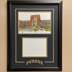 May include: A black framed diploma with a gold mat and a gold inscription of "Purdue". The top portion of the frame features a color illustration of a brick building with the text "Purdue University, West Lafayette, IN" and "Ted Comeau 1998".