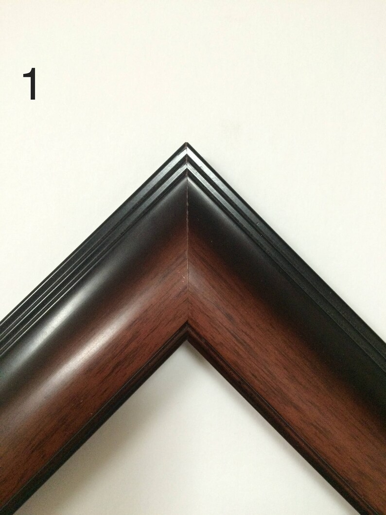 May include: Close-up of a corner of a picture frame. The frame has a dark brown wood grain interior and a black exterior. The number "1" is in the upper left corner of the image.