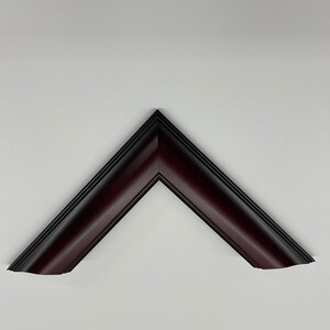 May include: A dark burgundy picture frame corner, angled at 90 degrees, against a white background. The frame has a beveled edge and a glossy finish, with a darker, almost black, inner edge.
