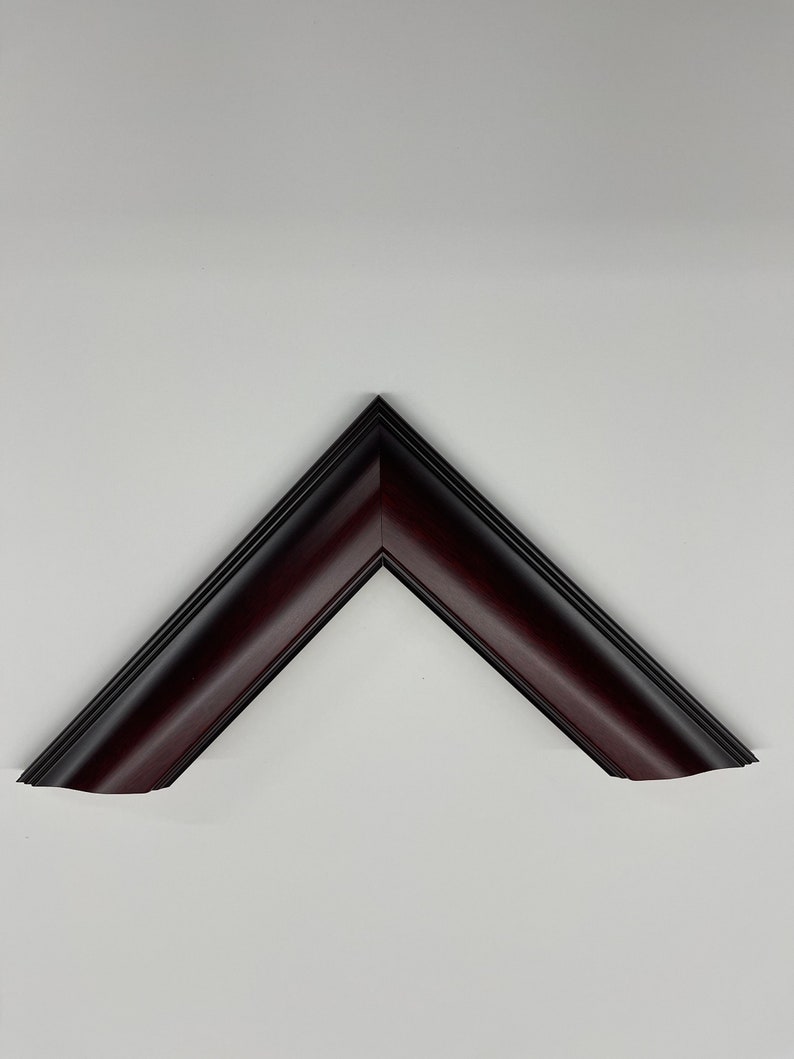 May include: A dark burgundy picture frame corner, angled at 90 degrees, against a white background. The frame has a beveled edge and a glossy finish, with a darker, almost black, inner edge.