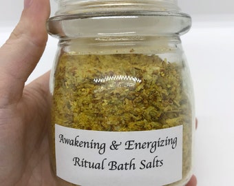 May include: A glass jar filled with yellow bath salts labeled "Awakening & Energizing Ritual Bath Salts".