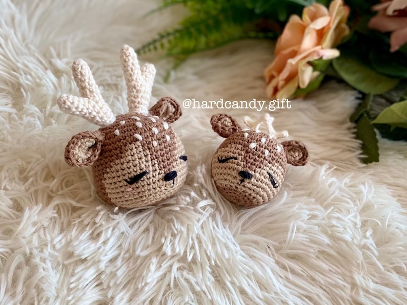 May include: Two crocheted deer plushies with brown and white fur, closed eyes, and black noses. The deer are lying on a white fluffy surface. The text "@hardcandy.gift" is visible in the background.