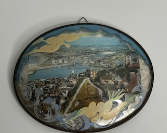 May include: A round, framed picture with a vintage image of a city skyline. The picture is in a brown frame with a silver-colored border. The image is of a city with a river running through it. The text "Le Havre" is visible in the image.