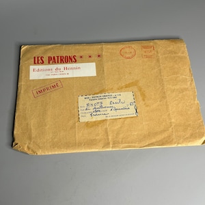 Puede incluir: Un sobre de papel marrón con el texto "LES PATRONS" y "Editions du Hennin" impreso en rojo. El sobre tiene un sello con el texto "IMPRIME" y una etiqueta con el texto "BON - PATRONS GRATUITS - VALABLE JUSQU'AU 15-11-1961" y "ANNOT LUCIEN - 14 Rue d'Authie - 80100 - Amiens - France".