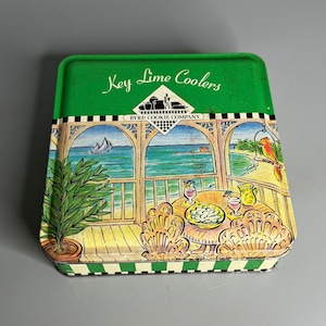 May include: Green tin with a white and green striped border. The tin has a picture of a porch with a table and chairs. The text on the tin reads "Key Lime Coolers" and "Byrd Cookie Company".