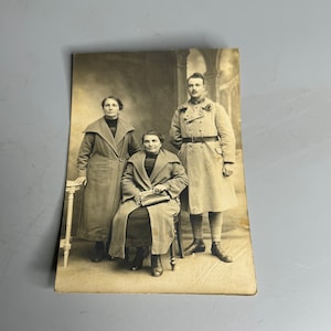 Ancienne carte postale photo en noir et blanc portrait de famille avec un soldat militaire hommes époque 1910