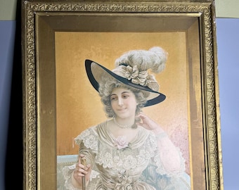 Puede incluir: Un retrato enmarcado de una mujer con un gran sombrero negro con una pluma blanca y un vestido de encaje. El fondo es de un amarillo suave.