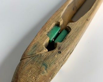 Peut inclure: Une navette en bois avec une extrémité pointue et une rainure pour le fil. La navette contient deux pièces en plastique vert à l'intérieur.