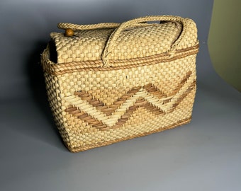 May include: A woven basket with a geometric pattern and two handles. The basket is made of natural materials and has a light brown color.