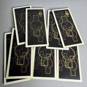 May include: A collection of playing cards with a black background and a gold geometric design. The cards have a white border and the word "Martini" is printed on the top of each card.