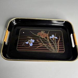 May include: Rectangular black serving tray with gold trim and woven handles. The tray features a floral design with brown, blue, and gold accents. The design is set against a background of brown horizontal stripes.