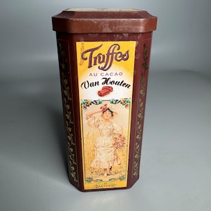 May include: A red and gold tin box with a vintage design. The box features a woman in a white dress holding a bouquet of flowers. The text on the box reads "Truffes au Cacao Van Houten Suchard".