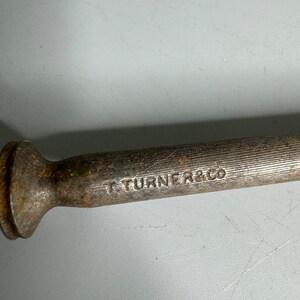 May include: A close-up of a metal tool with a rounded head and a textured body. The tool is marked with the text "T TURNER & CO".