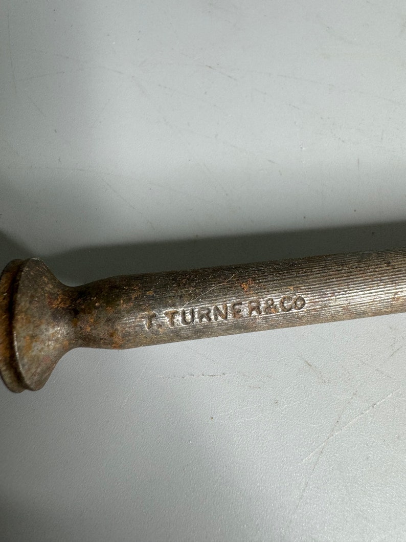 May include: A close-up of a metal tool with a rounded head and a textured body. The tool is marked with the text "T TURNER & CO".