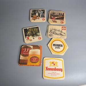 May include: A collection of vintage beer coasters featuring various brands, including Kronenbourg, 33 Export, and Pelfroth Pale. The coasters are made of cardboard and feature colorful illustrations and text.