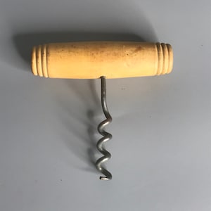 May include: A corkscrew with a wooden handle and a metal spiral. The handle is light brown and has a grooved design.
