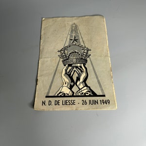 May include: A black and white illustration of a crown being held by two hands. The crown is surrounded by a wreath of leaves and has a star on top. The text "N.D. DE LIESS - 26 JUIN 1949" is at the bottom of the image.