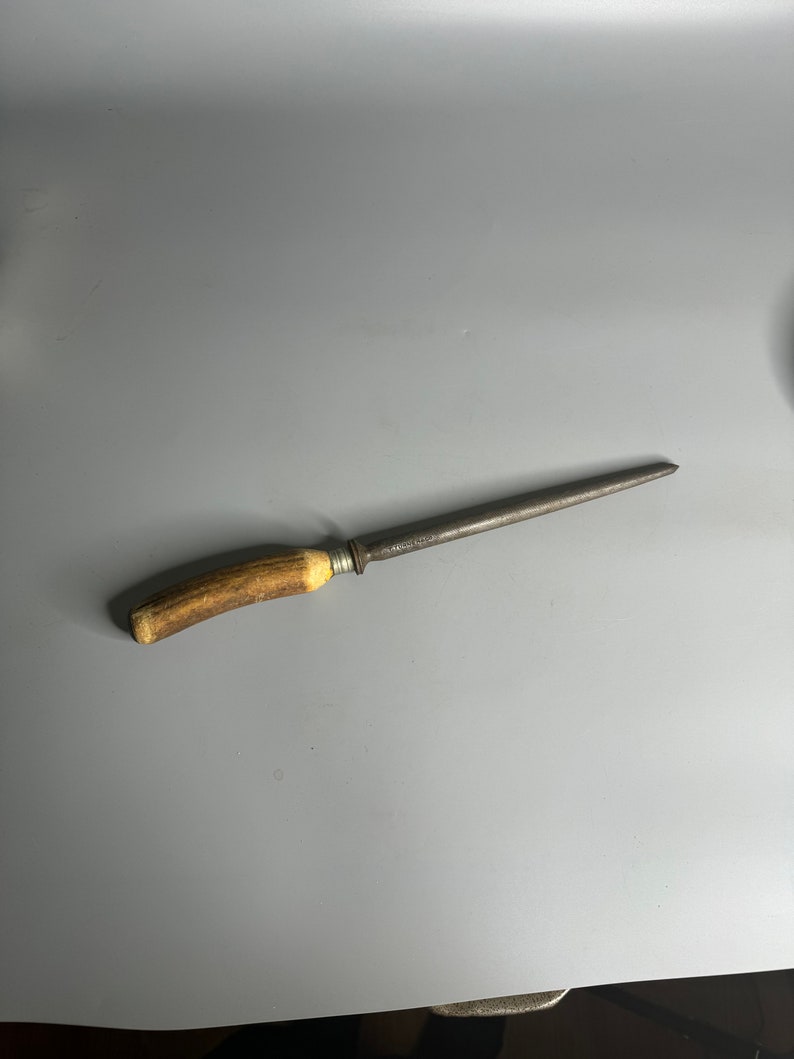 May include: A vintage steel knife sharpener with a brown antler handle. The sharpener is about 12 inches long.
