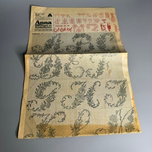 May include: A black and white cross stitch pattern with a floral design. The pattern is printed on a white paper with a grid. The title of the pattern is "Anna Burda Spezial an Handarbeiten" and the number is "0484/20, 42-46".