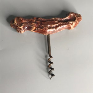 Può includere: Un cavatappi in ceramica marmorea marrone e bianca con una spirale in metallo.