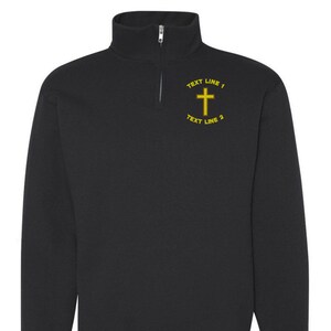 Könnte beinhalten: Schwarzes Sweatshirt mit Viertelreißverschluss und gelbem Kreuzdesign. Der Text "TEXT LINE 1" und "TEXT LINE 2" befindet sich über und unter dem Kreuz. Das Sweatshirt hat lange Ärmel und gerippte Bündchen.