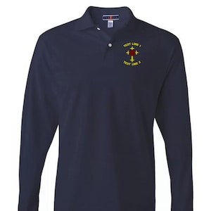 Puede incluir: Polo de manga larga azul marino con cuello y cierre de botones. La camisa presenta un emblema bordado con un diseño de cruz y rosa, y el texto "TEXT LINE 1" y "TEXT LINE 2" en amarillo.
