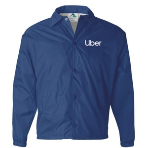 Peut inclure: Une veste bleue, légère, à boutons pression avec un logo "Uber" blanc brodé sur la poitrine gauche.