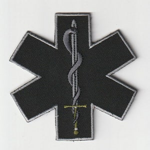 May include: Black embroidered patch in the shape of a star of life, a medical symbol. The patch features a gray sword entwined with a serpent, a common symbol in medicine. The edges are outlined in gray.