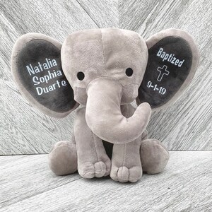 May include: A gray plush elephant with embroidered ears. One ear says "Natalia Sophia Duarte" and the other ear says "Baptized 9-1-19" with a cross.