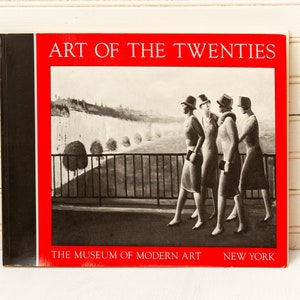 Może przedstawiać: Czerwona okładka książki z tytułem "Art of the Twenties" i tekstem "The Museum of Modern Art, New York". Okładka przedstawia czarno-białe zdjęcie czterech kobiet idących w rzędzie.