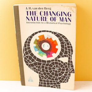 May include: A vintage book titled "THE CHANGING NATURE OF MAN" by J. H. van den Berg. The cover features a stylized head with a mosaic pattern and a colorful gear design inside. The book is set against a yellow background.