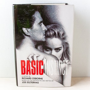 May include: A hardcover book titled "Basic Instinct" with a black and white image of a man and woman. The title is in large red letters. The author's name and the movie's writer are also listed.