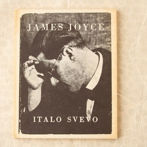 May include: A black and white photograph of James Joyce on the cover of a book. The book's title is "JAMES JOYCE" in large white lettering. Below the photo is the text "ITALO SVEVO" in white lettering.
