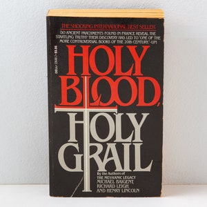 May include: A black book with the title "Holy Blood, Holy Grail" in red and grey lettering. The book is by the authors of "The Messianic Legacy" and features a white cross on the cover.