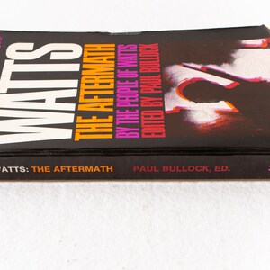 May include: A black book with the title "Watts: The Aftermath" by the people of Watts, edited by Paul Bullock. The book cover features a silhouette of a person against a red and white background.