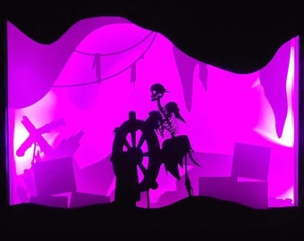 May include: A purple silhouette of a skeleton holding a ship's wheel, with other silhouettes of a ship's mast and rigging in the background.
