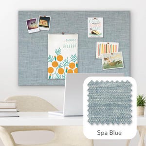 Pu&ograve; includere: Una bacheca in tessuto blu chiaro con vari elementi appuntati, tra cui un calendario, cartoline e foto. Il calendario mostra il mese di agosto. Un campione di tessuto &egrave; etichettato "Spa Blue".