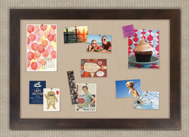 May include: A corkboard with a brown frame and a beige fabric surface. The corkboard is decorated with various photos, cards, and a sticky note that says "Let's make this!" The photos include a watercolor painting of red balloons, a photo of two people in the water, a photo of two people holding a watermelon, a photo of a cupcake, a photo of a woman in a kitchen, and a photo of a Ferris wheel. The cards include a baby shower invitation, a birthday card, and a card with a vintage design.