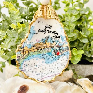 May include: Gold-painted oyster shell ornament with a nautical map of the Florida Keys. The map shows the location of Marathon, Vaca Key, and other points of interest. The ornament is decorated with the text "Griff Family Vacation 2024".