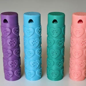 May include: Four cylindrical containers in purple, light blue, teal, and peach. Each container features a repeating embossed pattern of hearts with paw prints inside. The top of each cylinder has a small triangular cutout near the rim.