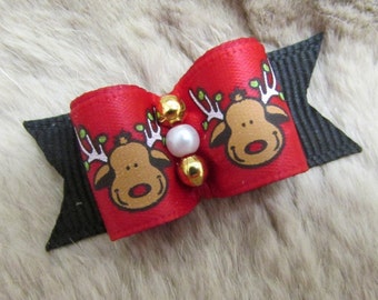 May include: A festive red bow with a reindeer design, accented with gold beads and a pearl. The bow features black ribbon ends. This holiday-themed accessory is perfect for pets.