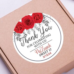 May include: Round thank you sticker with red roses and silver glitter. The sticker says "Thank You for celebrating with us!  Ny'Layjah Sweet 17 3/15/24"