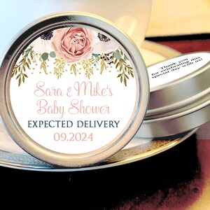 May include: A white round label with pink and white flowers, gold leaves, and gold glitter. The label says "Sara & Mike's Baby Shower" and "Expected Delivery 09.2024".