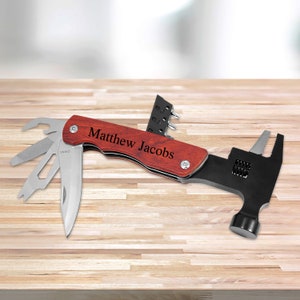 May include: A multi-tool with a wooden handle and a hammer head. The handle is engraved with the name "Matthew Jacobs".