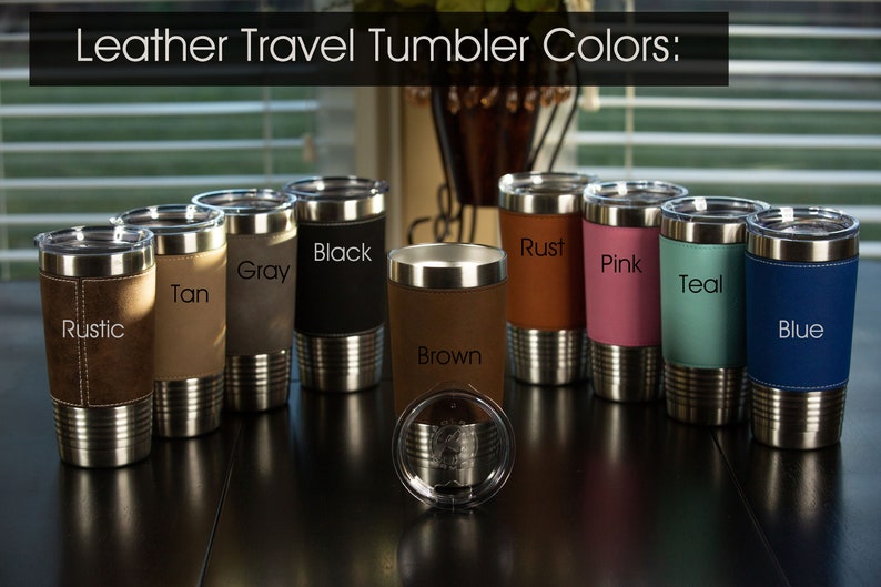 May include: Leather travel tumblers in various colors, including rustic, tan, gray, black, brown, rust, pink, teal, and blue. The tumblers have a stainless steel exterior and a leather-like wrap.