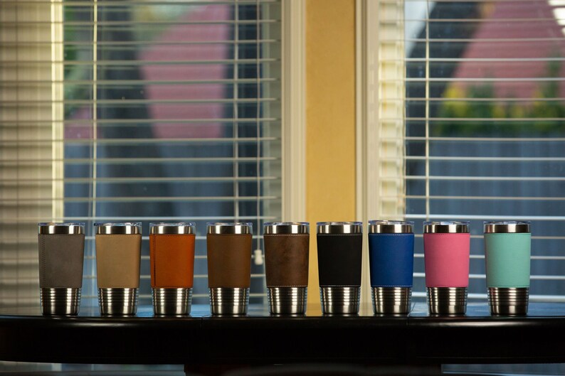 May include: Ten stainless steel travel mugs with different colored faux leather wraps. The colors are gray, beige, orange, brown, dark brown, black, blue, pink, and light blue.